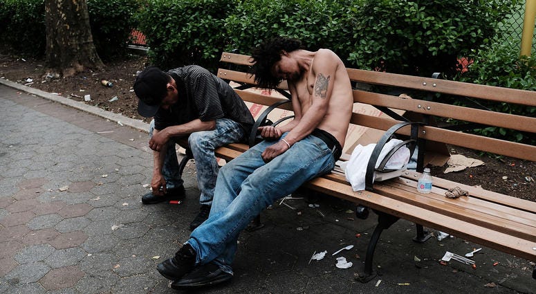 Men sit passed out in a park where heroin users gather to shoot up in the Bronx on May 4, 2018 in New York City. Heroin users