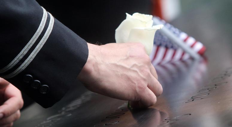 A flight attendant from Long Island, Gregory Davidowitch puts a flower in the name of his friend, Prokopios Paul Zios during ceremonies at the National September 11 Memorial