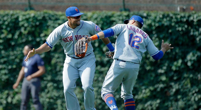 New York Mets right fielder Carlos Gomez (left) and left fielder Raphael Gladu (12) celebrate their win over the Chicago Cubs at Wrigley Field. The New York Mets won 10-2.