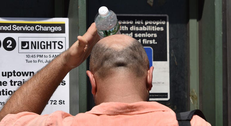 As day-time temperatures soar above the ninety degree mark, a man rubs his head with a cold plastic bottle of water to cool down at Columbus circle in New York, NY, on July 6, 2016. New York City Hot Weather