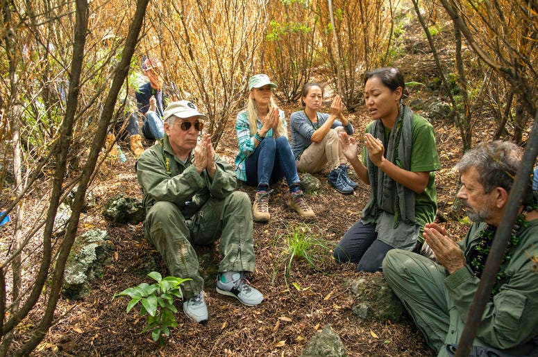 Paul Simon, left, joins in a prayer lead by Aimee Sato