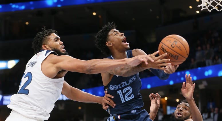 Memphis Grizzlies guard Ja Morant (12) is fouled in the fourth quarter by Minnesota Timberwolves center Karl Anthony Towns (32) as forward Andrew Wiggins (22) and forward Treveon Graham (12) look on at FedExForum. Memphis won 137-121.