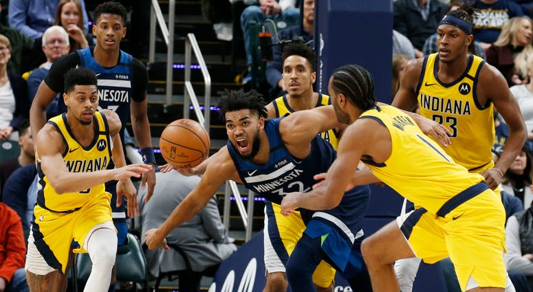 Minnesota Timberwolves center Karl Anthony-Towns (32) loses control of the ball as Indiana Pacers guard Jeremy Lamb (26) and forward T.J. Warren (1) chase after the ball during the fourth quarter at Bankers Life Fieldhouse. Timberwolves