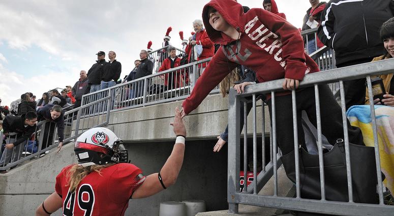 A young fan congratulates St. Cloud State University players as they leave the field after a game in 2014
