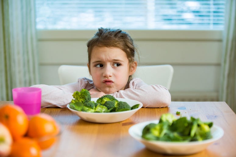Girl eating spinach and broccoli at the table