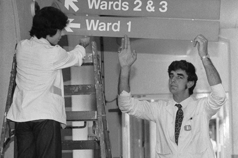 English actor Peter Mayhew (right) helps put up signs to the wards at King's College Hospital, where he works as an orderly, 3rd June 1977. Mayhew, who is 7'3'' tall English actor Peter Mayhew (right) helps put up signs to the wards at King's College Hospital, where he works as an orderly, 3rd June 1977. Mayhew, who is 7'3'' tall