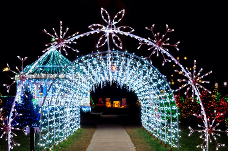 A tunnel of Christmas lights adds a bright note to a festive village outdoor display A tunnel of Christmas lights adds a bright note to a festive village outdoor display