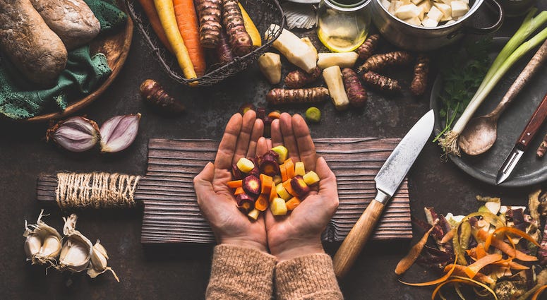 Female woman hands holding diced colorful vegetables on rustic kitchen table with vegetarian cooking ingredients and tools. Health Female woman hands holding diced colorful vegetables on rustic kitchen table with vegetarian cooking ingredients and tools. Health