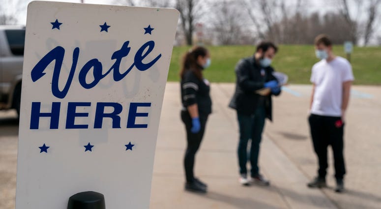 Poll worker Josh Harrison, center, works with Chad Donahue, right, during curbside voting on April 7, 2020 in Madison, Wisconsin.