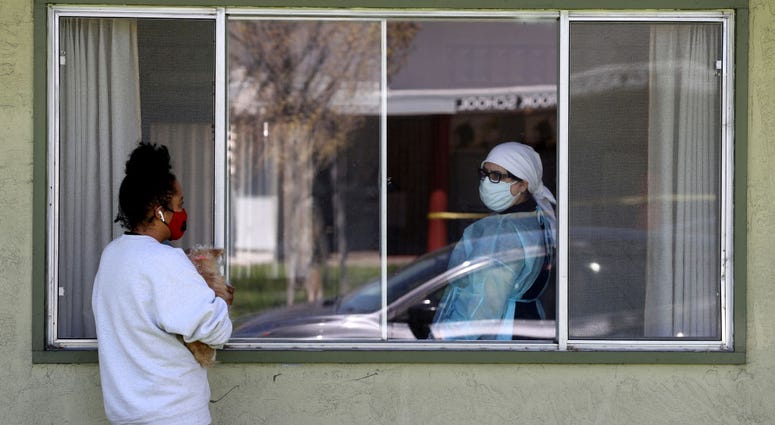 Adrina Rodriguez (L) talks with a nurse through a window as she visits her father who is a patient at the Gateway Care and Rehabilitation Center that has tested negative for COVID-19 on April 14, 2020 in Hayward, California.