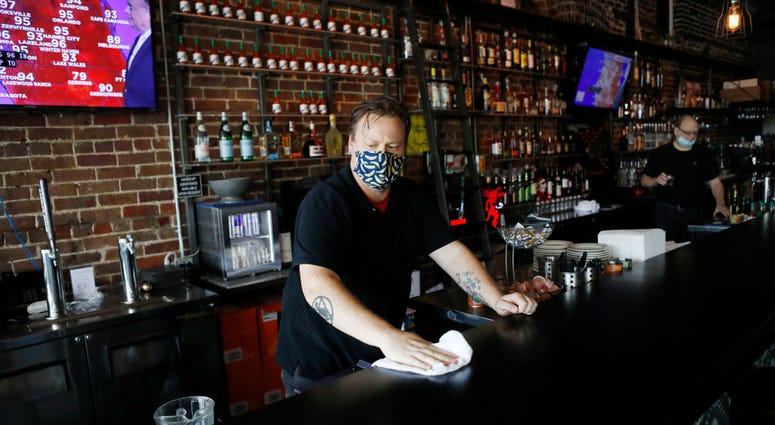 Zack Vermes a bartender at Carmines Ybor Italian restaurant wipes off the bar while awaiting patrons on June 26, 2020 in Tampa, Florida.