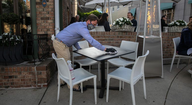 An employee at Terra restaurant cleans an outdoor table on May 20, 2020 in Greenwich, Connecticut.