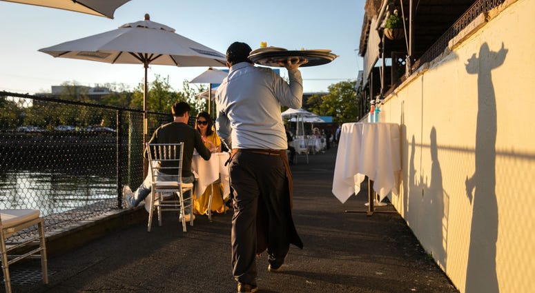 : A waiter serves patrons at L'escale restaurant on May 20, 2020 in Greenwich, Connecticut. : A waiter serves patrons at L'escale restaurant on May 20, 2020 in Greenwich, Connecticut.