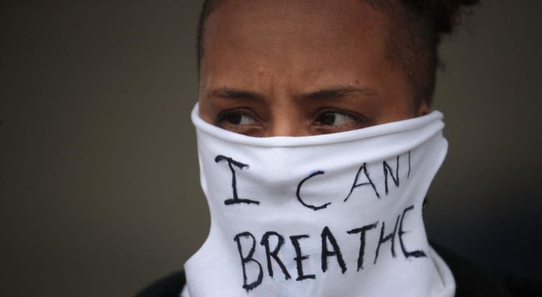 A person wears a mask that reads "I CAN'T BREATHE" as demonstrators continue to protest the death of George Floyd following a night of rioting on May 29, 2020 in Minneapolis, Minnesota.