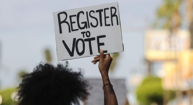 A protester carries a 'Register to Vote' sign during a peaceful demonstration against racism and police brutality on June 06, 2020 in Los Angeles, California