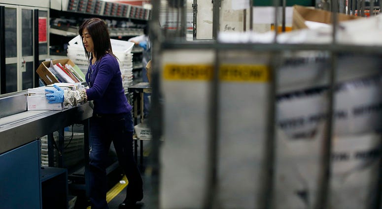 An United States Postal Office employee puts a bundle of mail onto a machine at the Processing and Distribution Center on December 16, 2013 in San Francisco, California