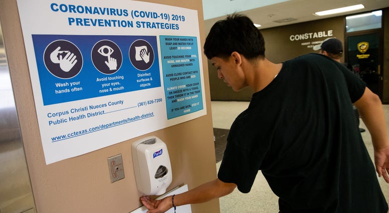 A man uses hand sanitizer underneath a coronavirus prevention sign at the entrance of the Nueces County Courthouse on Friday, March 13, 2020. Covid 19 Corpus 6