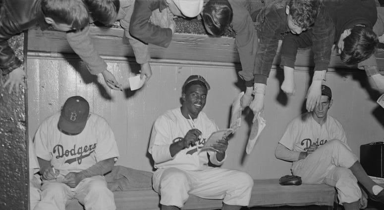 Jackie Robinson and teammates signing autographs for fans in 1949