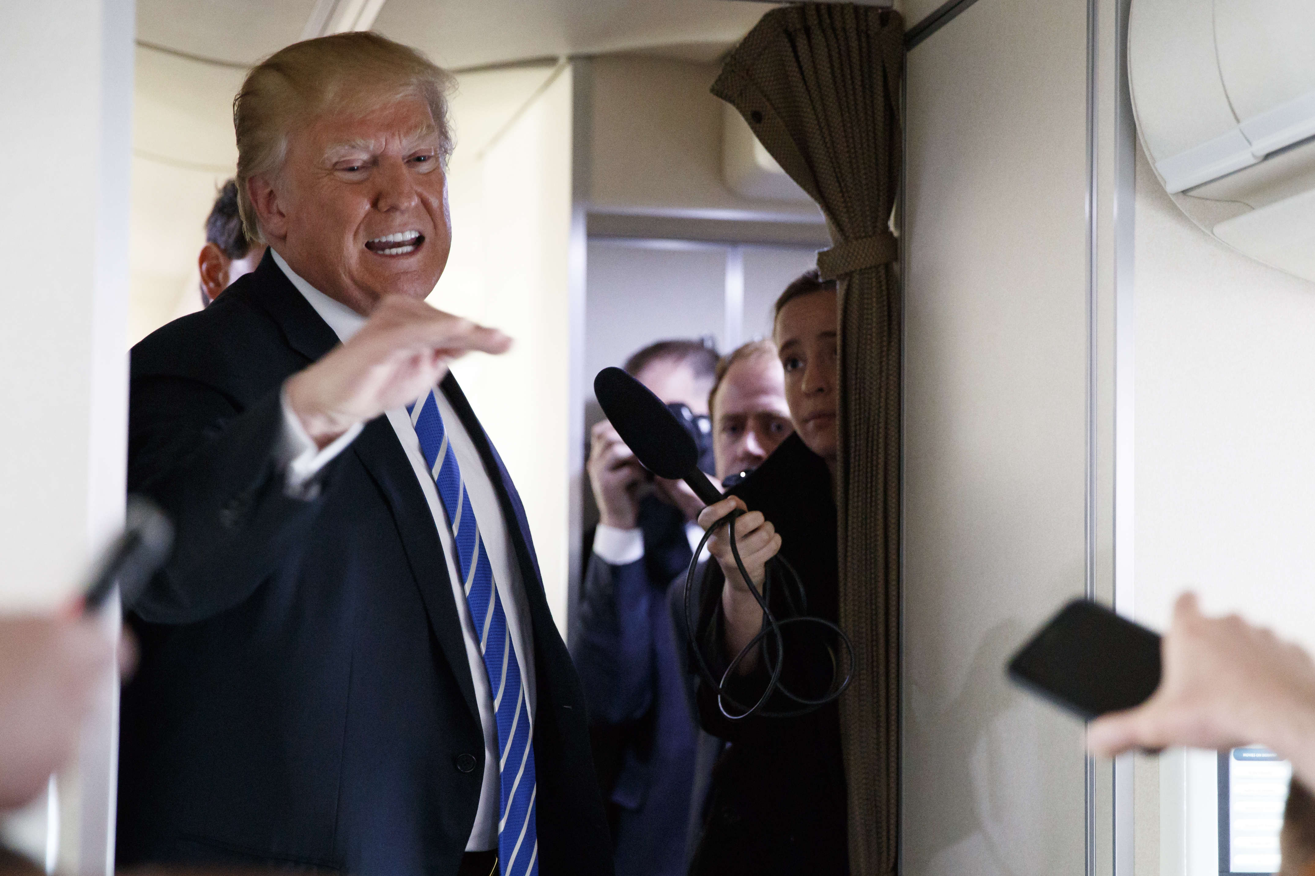 President Donald Trump talks with reporters aboard Air Force One on a flight to Andrews Air Force Base, Md.