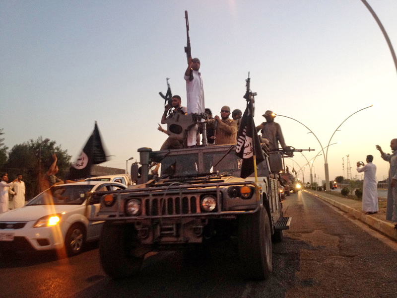 In this June 23, 2014 file photo, fighters from the Islamic State group parade in a commandeered Iraqi security forces armored vehicle on the main road in Mosul, Iraq. In this June 23, 2014 file photo, fighters from the Islamic State group parade in a commandeered Iraqi security forces armored vehicle on the main road in Mosul, Iraq.