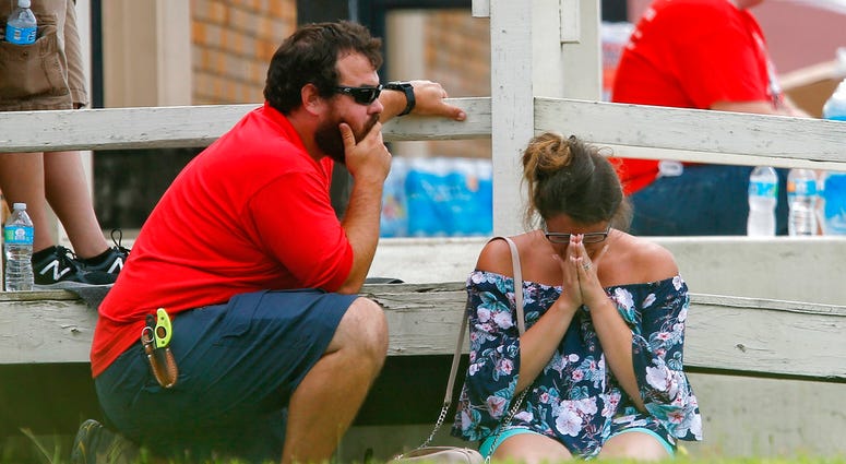 A woman prays in the grass outside the Alamo Gym where parents wait to reunite with their kids following a shooting at Santa Fe High School Friday, May 18, 2018, in Santa Fe, Texas. (Michael Ciaglo/Houston Chronicle via AP)