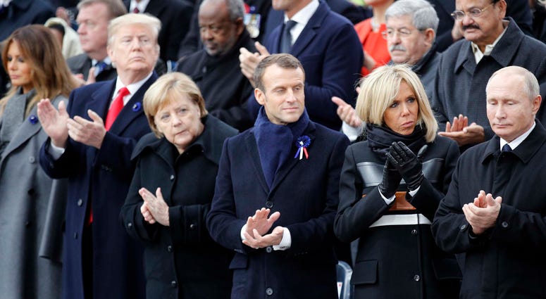 U.S President Donald Trump, second left, and first lady Melania Trump, left, German Chancellor Angela Merkel, third left, French President Emmanuel Macron and his wife Brigitte, Russian President Vladimir Putin, right, applaud after ceremonies at the Arc World War I