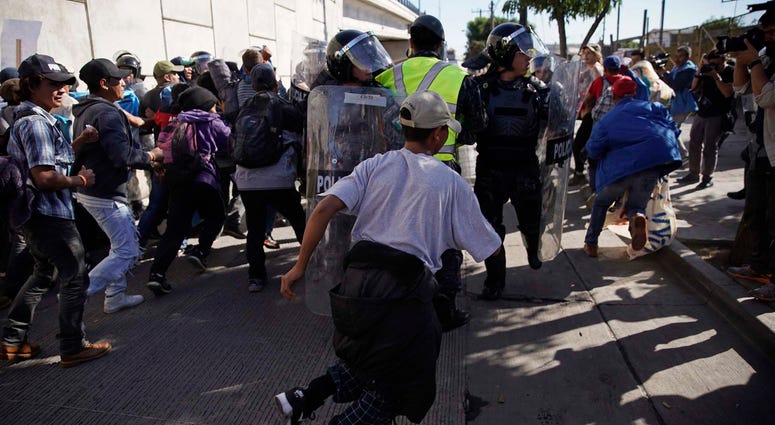 Migrants break past a line of police as they run toward the Chaparral border crossing in Tijuana, Mexico, Sunday, Nov. 25, 2018. migrant caravan