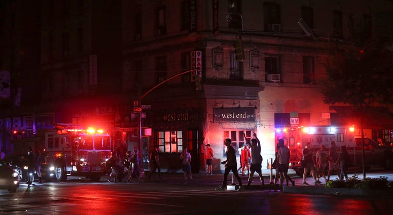 Pedestrians cross the street near emergency response vehicles at 50th Street and 8th Avenue during a power outage, Saturday, July 13, 2019, in New York. Blackout NYC AP