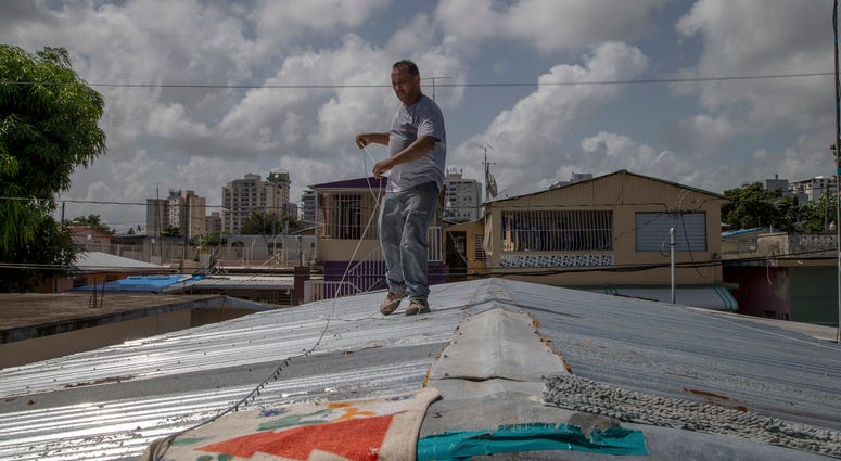 Jorge Ortiz works to tie down his roof as he prepares for the arrival of Tropical Storm Dorian, in the Martín Peña neighborhood of San Juan, Puerto Rico, Tuesday, Aug. 27, 2019. The construction worker was taking no chances as Dorian approaches. Jorge Ortiz works to tie down his roof as he prepares for the arrival of Tropical Storm Dorian, in the Martín Peña neighborhood of San Juan, Puerto Rico, Tuesday, Aug. 27, 2019. The construction worker was taking no chances as Dorian approaches.