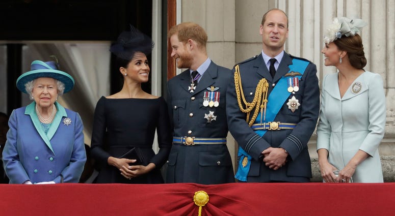 In this Tuesday, July 10, 2018 file photo Britain's Queen Elizabeth II, and from left, Meghan the Duchess of Sussex, Prince Harry, Prince William and Kate the Duchess of Cambridge watch a flypast of Royal Air Force aircraft pass over Buckingham Palace in Queen Elizabeth