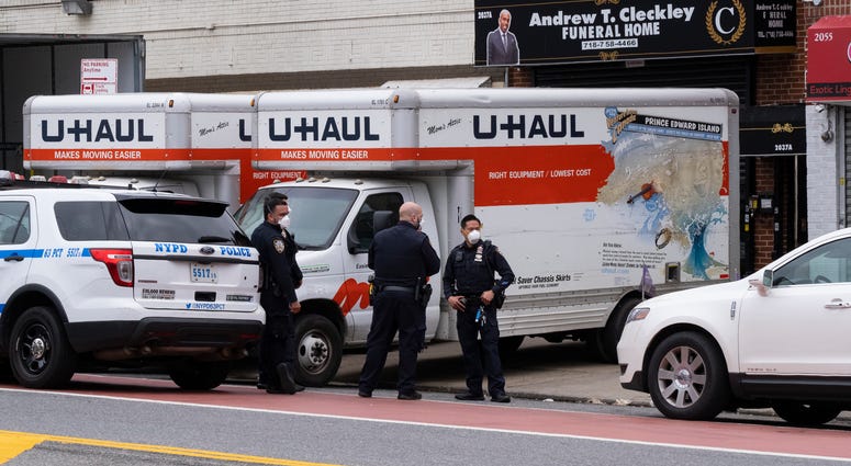 New York City police officers stand by at the Andrew T. Cleckley Funeral Home in the Brooklyn borough of New York, Wednesday, April 29, 2020. U-Haul trucks outside of the funeral home