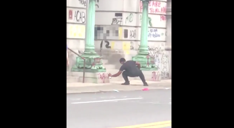 Video shows police nearby as the man sprays graffiti near the courthouse. Courthouse graffiti