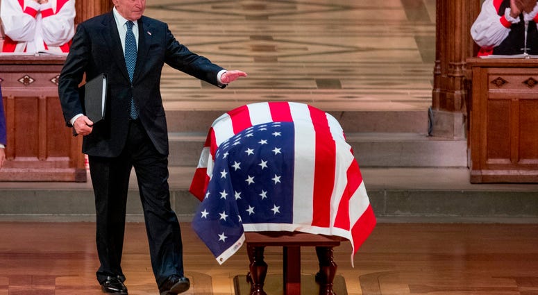 An emotional former President George Bush touches the flag-draped casket of his father, former President George H.W. Bush, after speaking during his State Funeral at the National Cathedral, Wednesday, Dec. 5, 2018, in Washington. George H.W. Bush