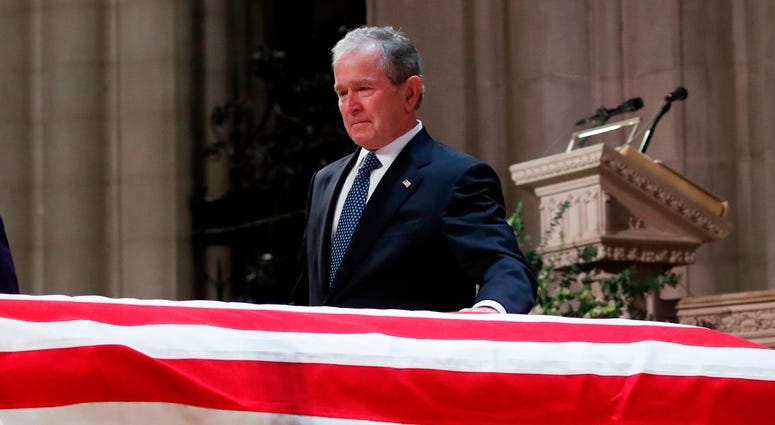 Former President George W. Bush touches the casket of his father, former President George H.W. Bush, at the State Funeral at the National Cathedral, Wednesday, Dec. 5, 2018, in Washington. George H.W. Bush