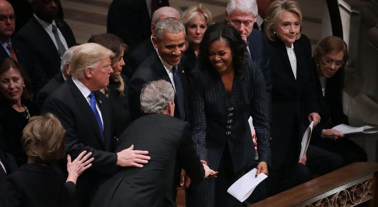 Former U.S. President George W. Bush (C) leans across President Donald Trump and first lady Melania Trump to greet fellow former presidents Barack Obama, Bill Clinton and former first ladies Rosalynn Carter, Hillary Clinton and Michelle Obama. George H.W. Bush