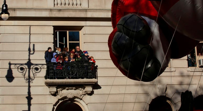 People on a balcony watch the 92nd annual Macy's Thanksgiving Day Parade on November 22, 2018 in New York City. Thanksgiving Day Parade 2018