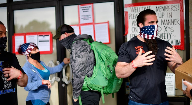Employees confer with patrons lining up outside the Atilis Gym on May 20, 2020 in Bellmawr, New Jersey. NJ gym