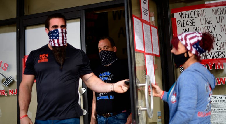 Employees exit to greet patrons lining up outside the Atilis Gym on May 20, 2020 in Bellmawr, New Jersey. Atilis Gym