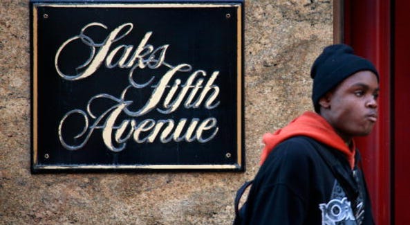 A pedestrian walks past a Saks Fifth Avenue store. A pedestrian walks past a Saks Fifth Avenue store.
