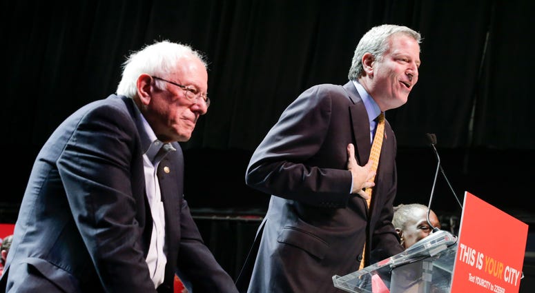 New York City Mayor Bill de Blasio (R) speaks to supporters next to Sen. Bernie Sanders (I-VT) as they take part in a campaign rally on October 30, 2017 in New York City. Sanders De Blasio