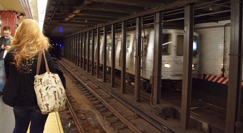 Passengers wait on the platform of a NYC subway station Subway train station