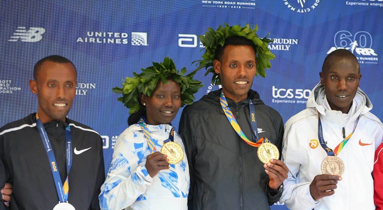 Mens winner Lelisa Desisa of Ethiopia (center) and womens winner Mary Keitany of Kenya pose during the medal ceremony with Shura Kitata of Ethiopia (left) and Geoffrey Kamworor of Kenya (far right) after the New York City Marathon. NYC Marathon