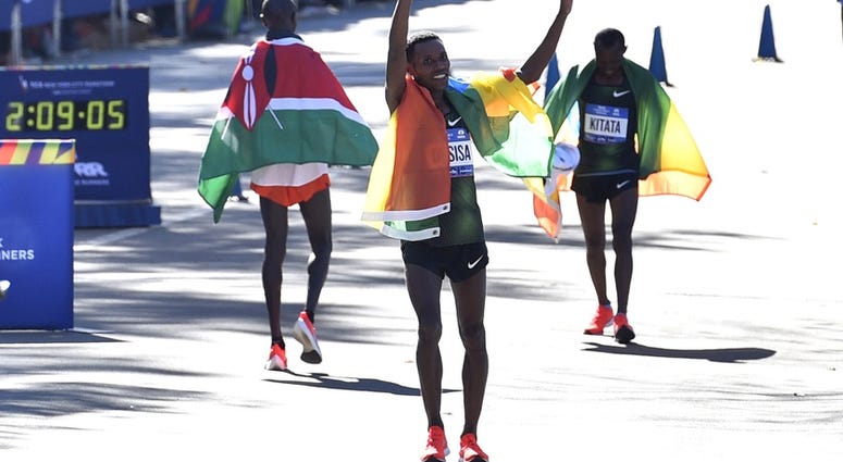 Lelisa Desisa, center, takes a victory lap after winning the professional men's division race of the 2018 TCS New York City Marathon. NYC Marathon