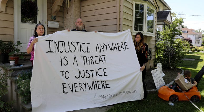 Doreen Limato, and her son-in-law Dan Brown and daughter Avisia Brown, are pictured at Doreen's home in Eastchester, with a sheet painted with \"Injustice anywhere is a threat to justice everywhere\" quote, June 16, 2020. Black Lives Matter banner Westchester