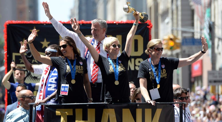 Carli Lloyd (left), Megan Rapinoe (center), New York City mayor Bill De Blasio (rear) and USA head coach Jill Ellis (right) make their way up Broadway in a ticker tape parade. World Cup parade 2015