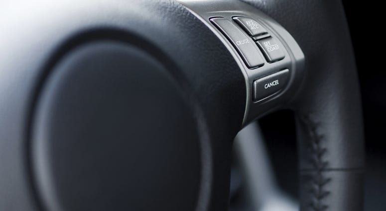 A close-up of cruise control buttons on a steering wheel. Shallow depth of field, focus on buttons. A close-up of cruise control buttons on a steering wheel. Shallow depth of field, focus on buttons.