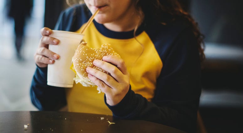 Overweight young person eating fast food. Obesity