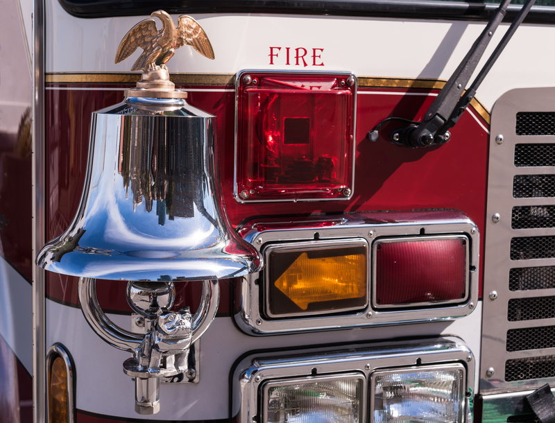Bright chrome and brass bell on the front of a fire truck and front lights. Bright chrome and brass bell on the front of a fire truck and front lights.