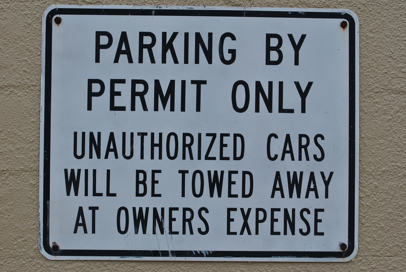 Parking By Permit Only Unauthorized Cars Will Be Towed Away At Owners Expense sign. Parking By Permit Only Unauthorized Cars Will Be Towed Away At Owners Expense sign.