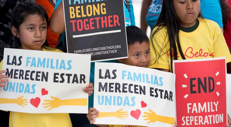 FILE - In this June 1, 2018, file photo, children hold signs during a demonstration in front of the Immigration and Customs Enforcement offices in Miramar, Fla. FILE - In this June 1, 2018, file photo, children hold signs during a demonstration in front of the Immigration and Customs Enforcement offices in Miramar, Fla.